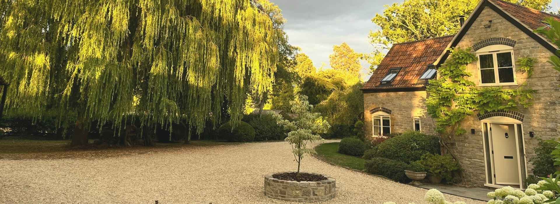 Courtyard with tree and cottage in background banner.