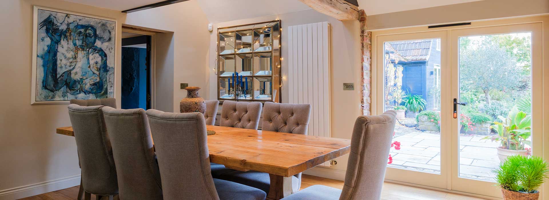 Picture of Dining Table with Door to the Outside in Background & Art on Wall.